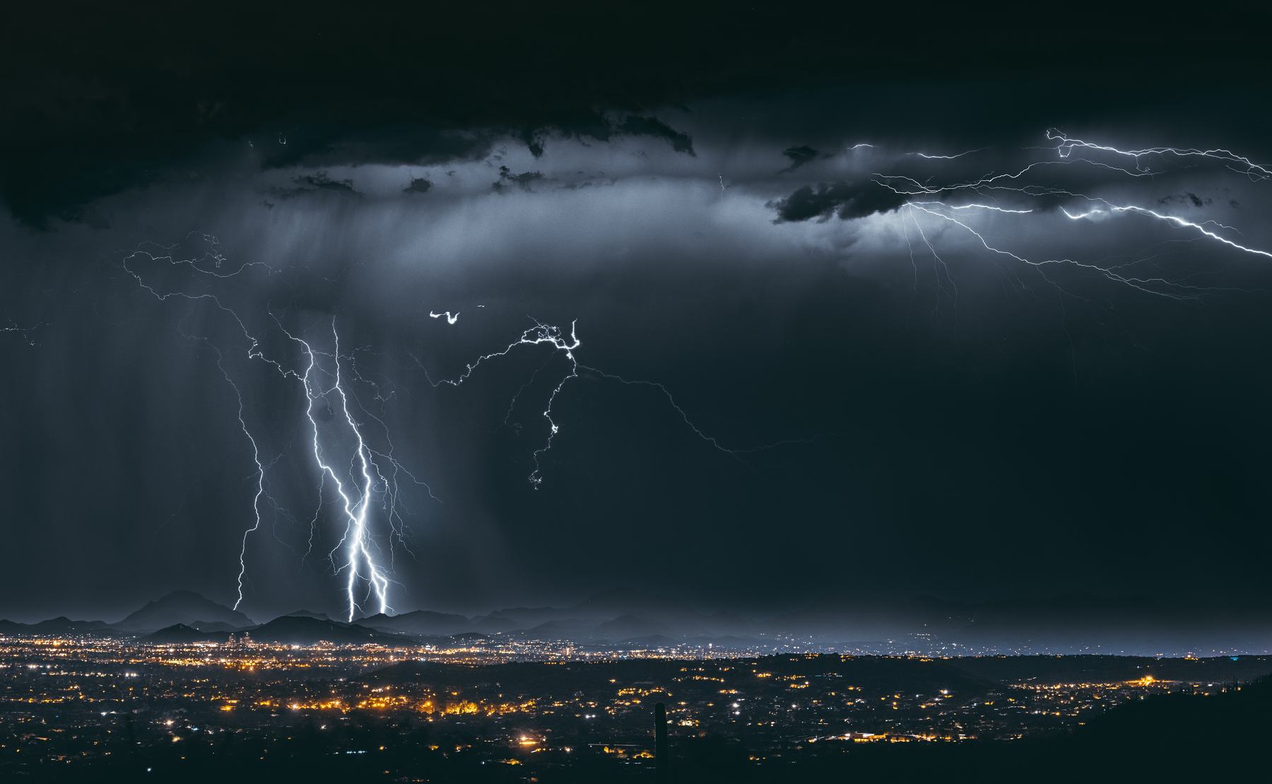 Huge lightning bolts striking over the lights of the Tucson Valley at night