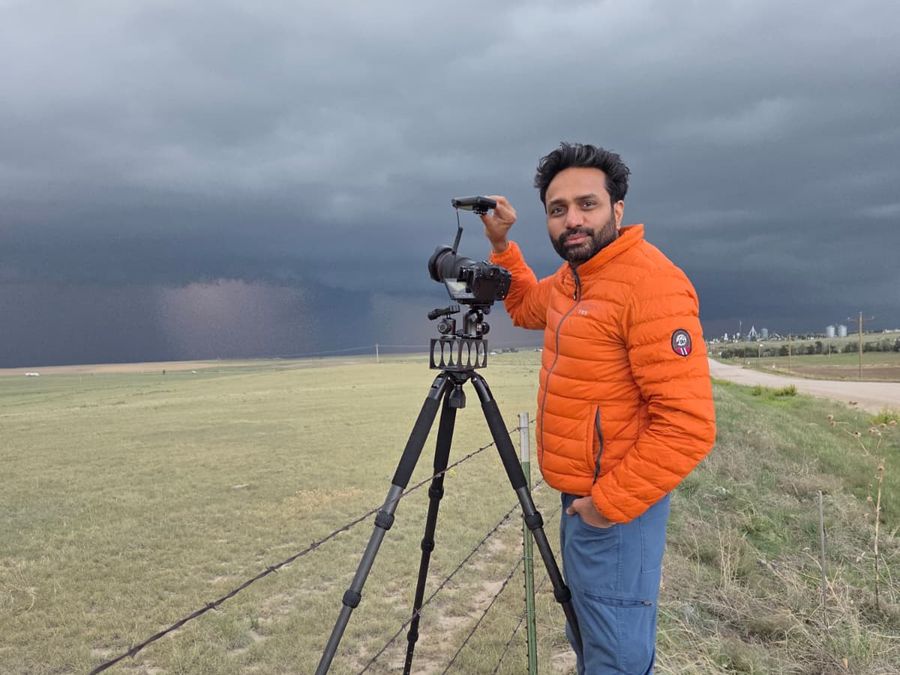 Setul Patel with his camera on a tripod under a darkening storm sky